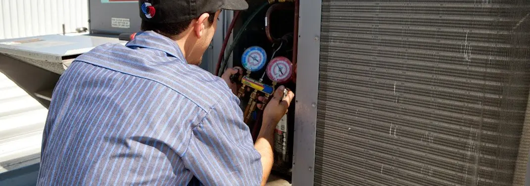 HVAC technician servicing a condenser unit in Dolton